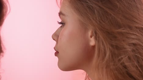 close-up profile of young woman and her reflection on pink background