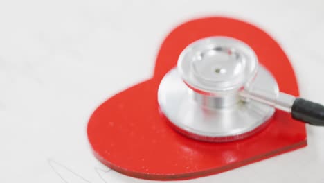 Video-of-close-up-of-heart-and-stethoscope-on-white-background