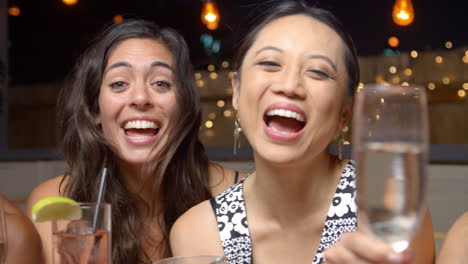 female friends enjoying night out at rooftop bar, slow motion