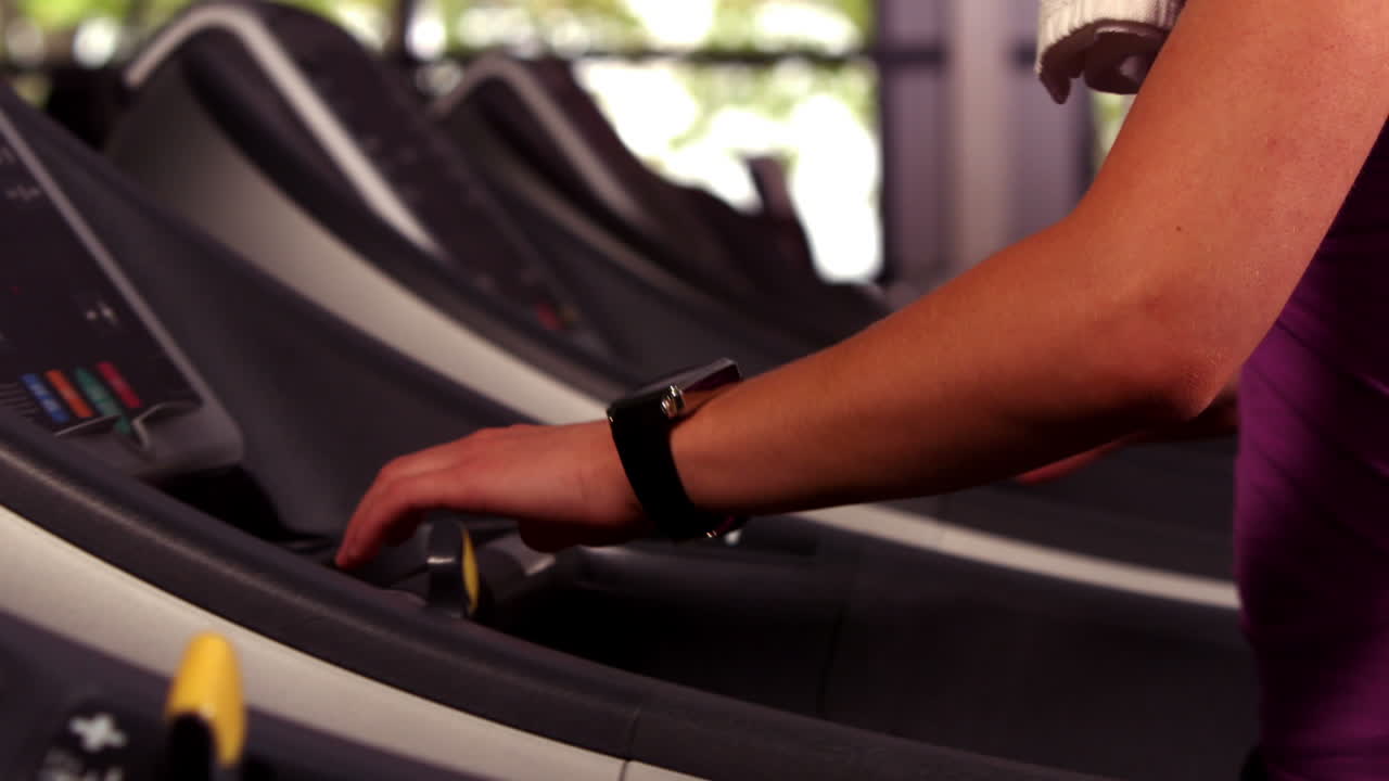 Fit woman running on the treadmill with a connected watch