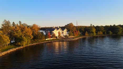 Vista-Aérea-Cinematográfica-De-Una-Casa-Del-Lago,-Lujosa-Propiedad-Inmobiliaria-Frente-A-Una-Maravillosa-Puesta-De-Sol