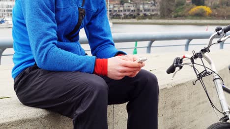 Biker-sitting-next-to-the-bike-and-using-mobile-phone,-4K-4k