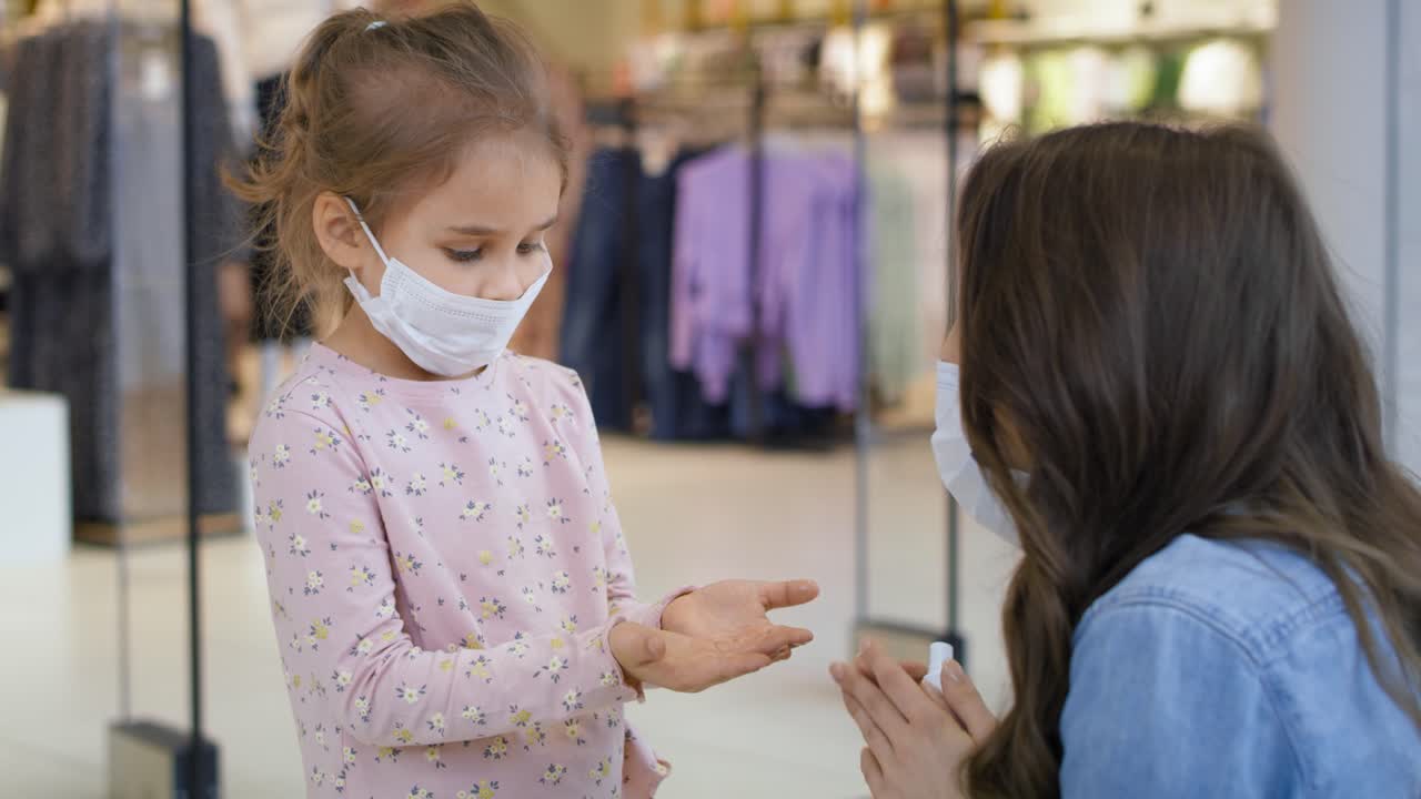 Mother sanitizing her daughter's hands with antibacterial hand spray