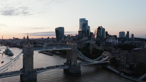 Aerial-view-of-traffic-of-Tower-Bridge-and-tall-modern-office-buildings-in-City-business-hub.-Colourful-sunset-sky.-London,-UK