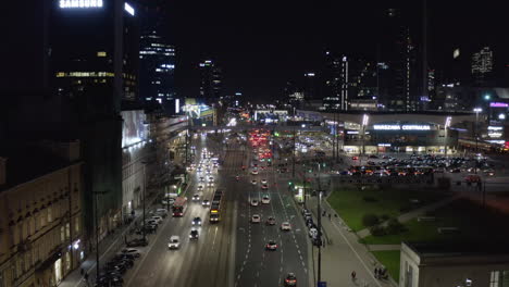 Imágenes-Crecientes-De-Tráfico-Pesado-En-El-Centro-De-La-Ciudad-Por-La-Noche.-Amplia-Carretera-De-Varios-Carriles-Que-Conduce-Entre-Edificios-De-Gran-Altura-Y-La-Estación-De-Tren.-Varsovia,-Polonia