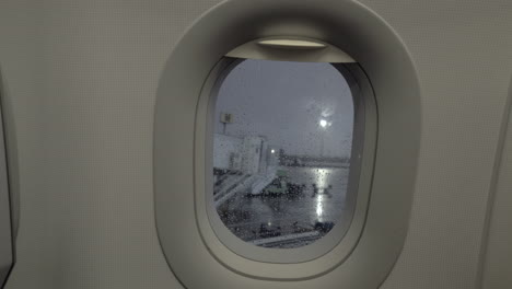 a closeup of a porthole and a rainy airport courtyard behind it