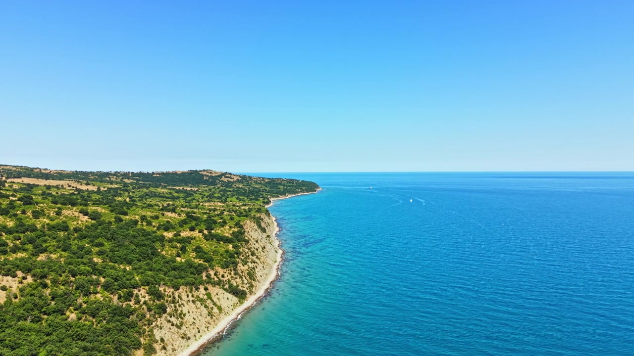 Veduta costiera dell'oceano con acqua cristallina e azzurra e terra in lontananza in una giornata di sole