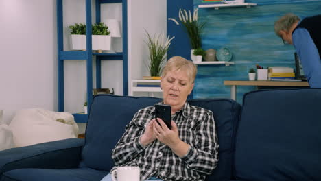 Overjoyed-middle-aged-woman-sitting-on-couch-in-living-room