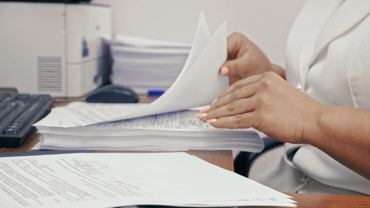 Donna d'affari in tailleur bianco che lavora con documenti in ufficio