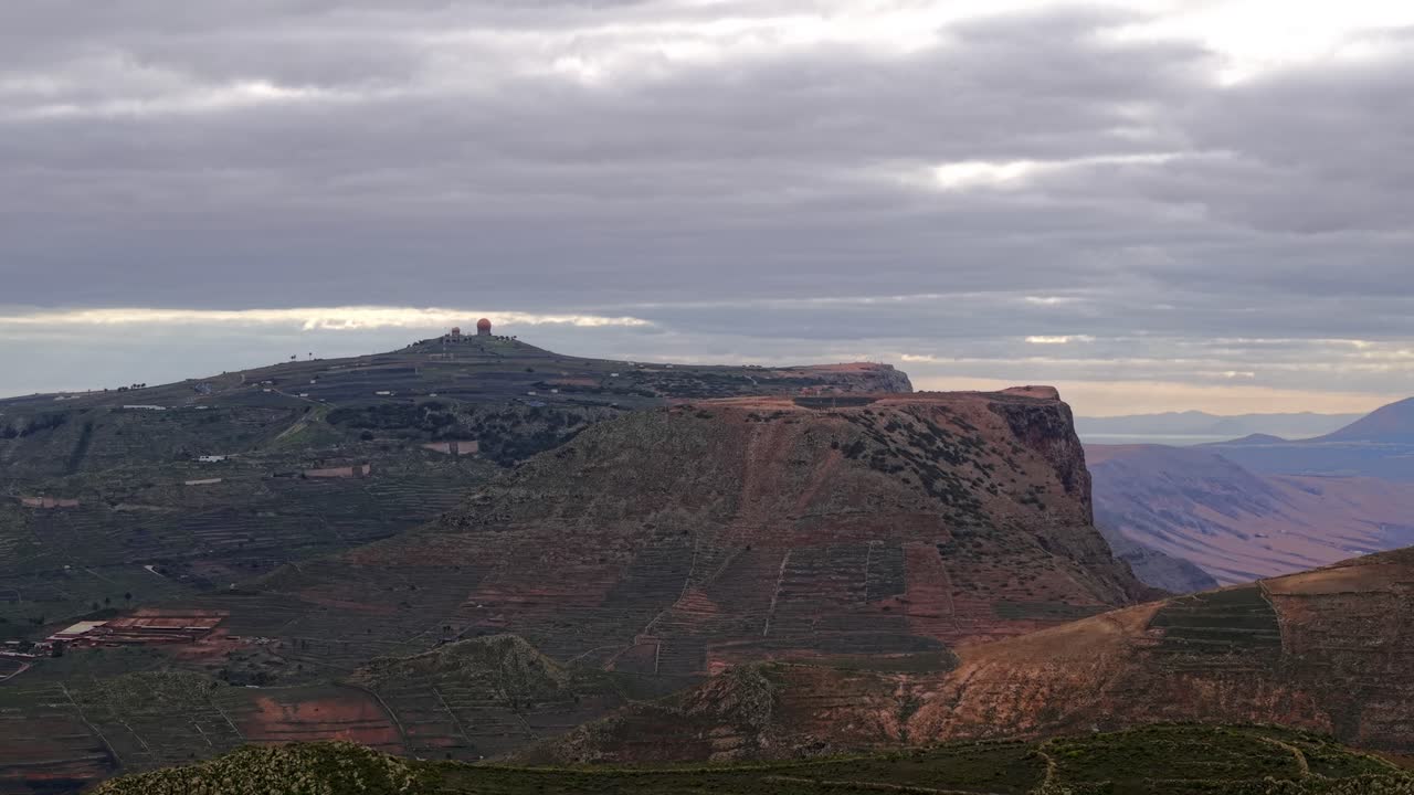 Vista panoramica di terrazzamenti agricoli su pendii vulcanici vicino al Mirador de Gayo sotto un cielo nuvoloso a Lanzarote, Spagna. Drone aereo in ascesa, spazio per il testo.