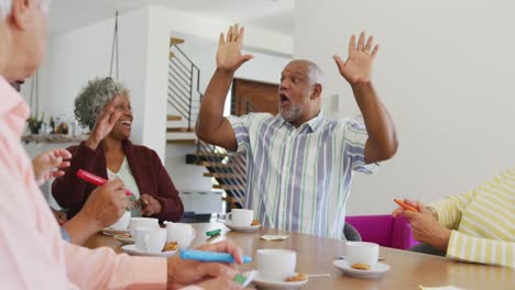 personas mayores felices y diversas bebiendo té y jugando al bingo en el hogar de ancianos