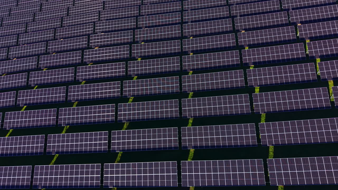 Ampia veduta di pannelli solari collocati su un ampio campo a mezzogiorno in una zona rurale, che mostrano file di fonti di energia rinnovabile che catturano la luce solare.