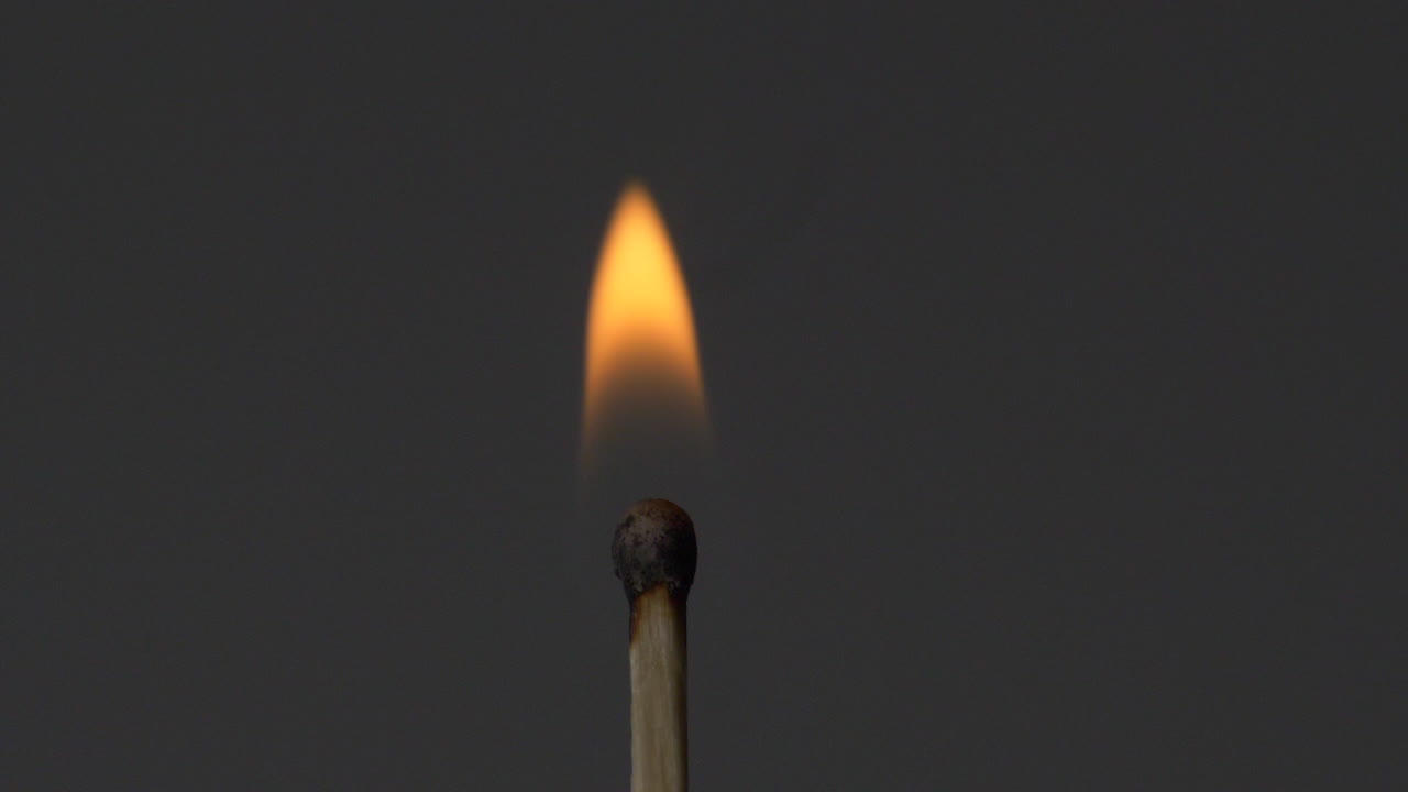 A burning match in grey background - close up