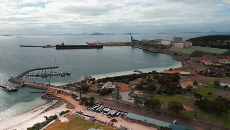 aerial view over esperance industrial harbour with a cargo ship beeing loaded on an overcast day, western australia