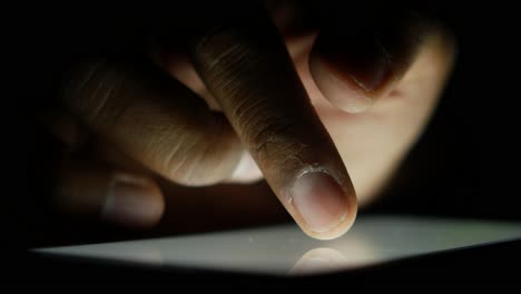 close up of a person's finger touching a smartphone screen in the dark