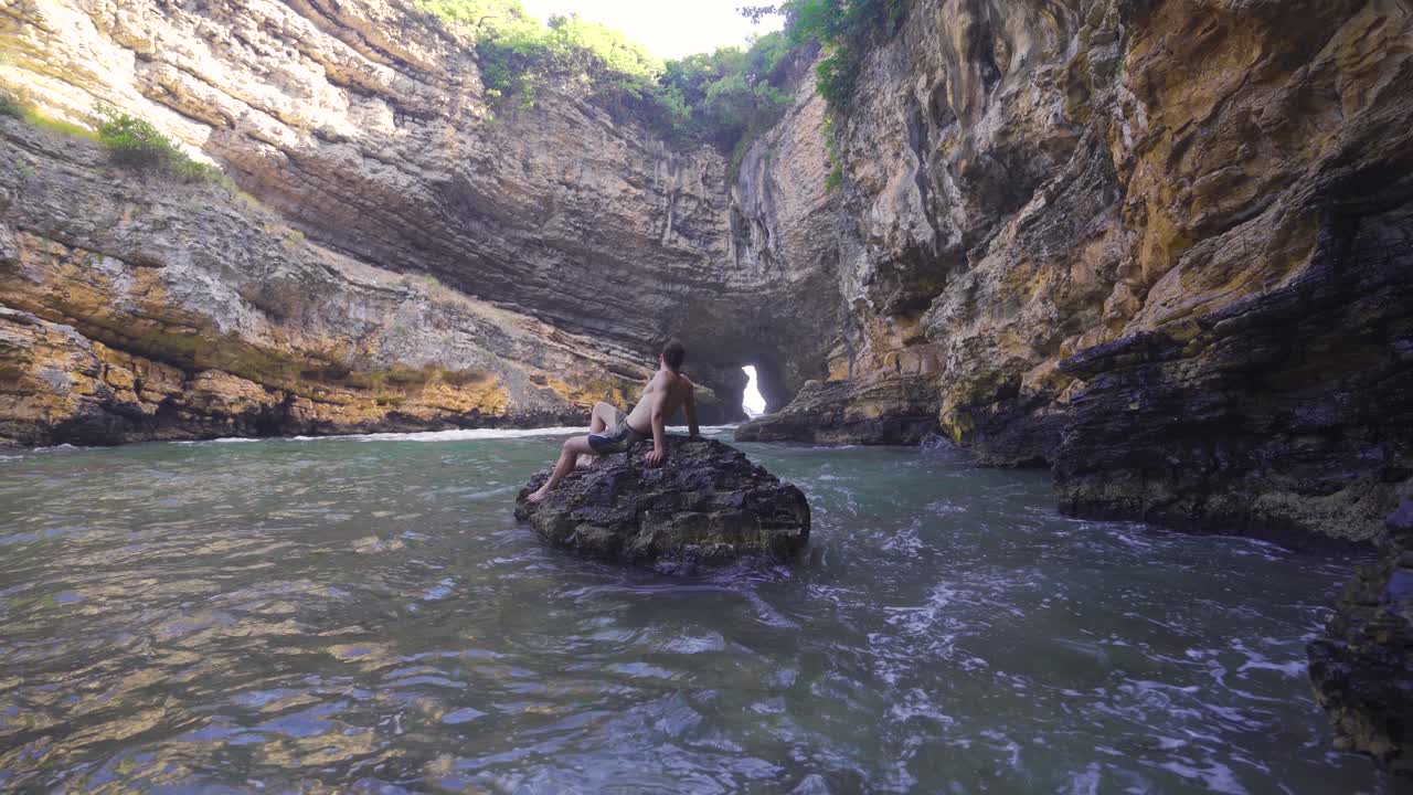 hombre atractivo en una cueva de la playa.