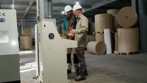 factory workers inspecting and operating industrial machine