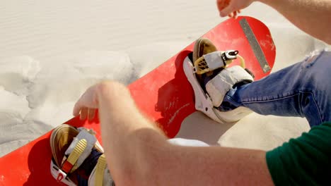 Man-attaching-the-sand-board-to-his-footwear-4k