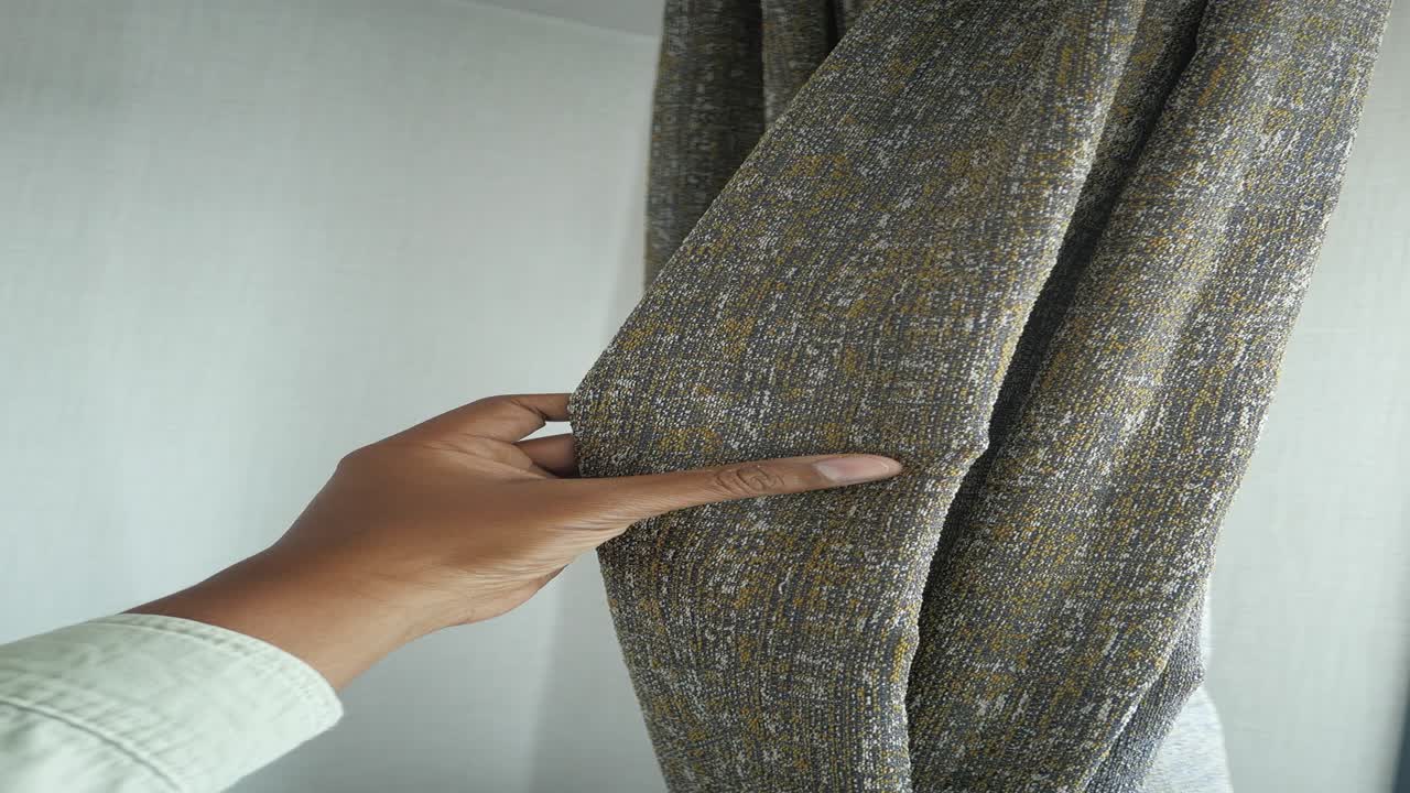 persona tocando una cortina gris