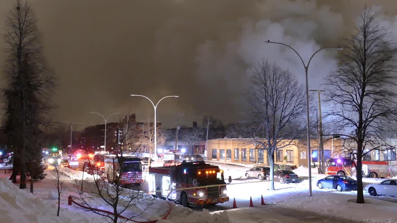 Fire trucks and smoke fill snowy Montréal street during large winter building fire