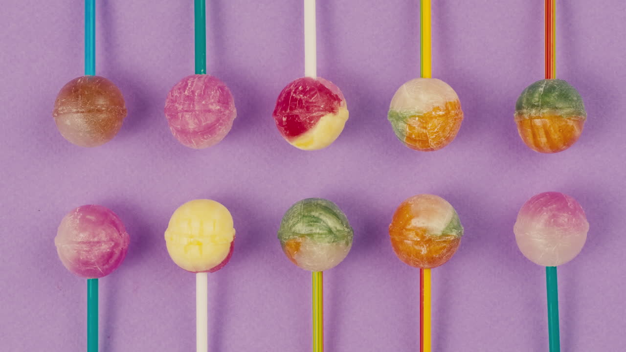 Sweet lollipops on color purple background zoom frame . Bright texture sugar candies close up top view. Composition of favorite children's summer sweets. Studio shot for shop, supermarket, confectionery