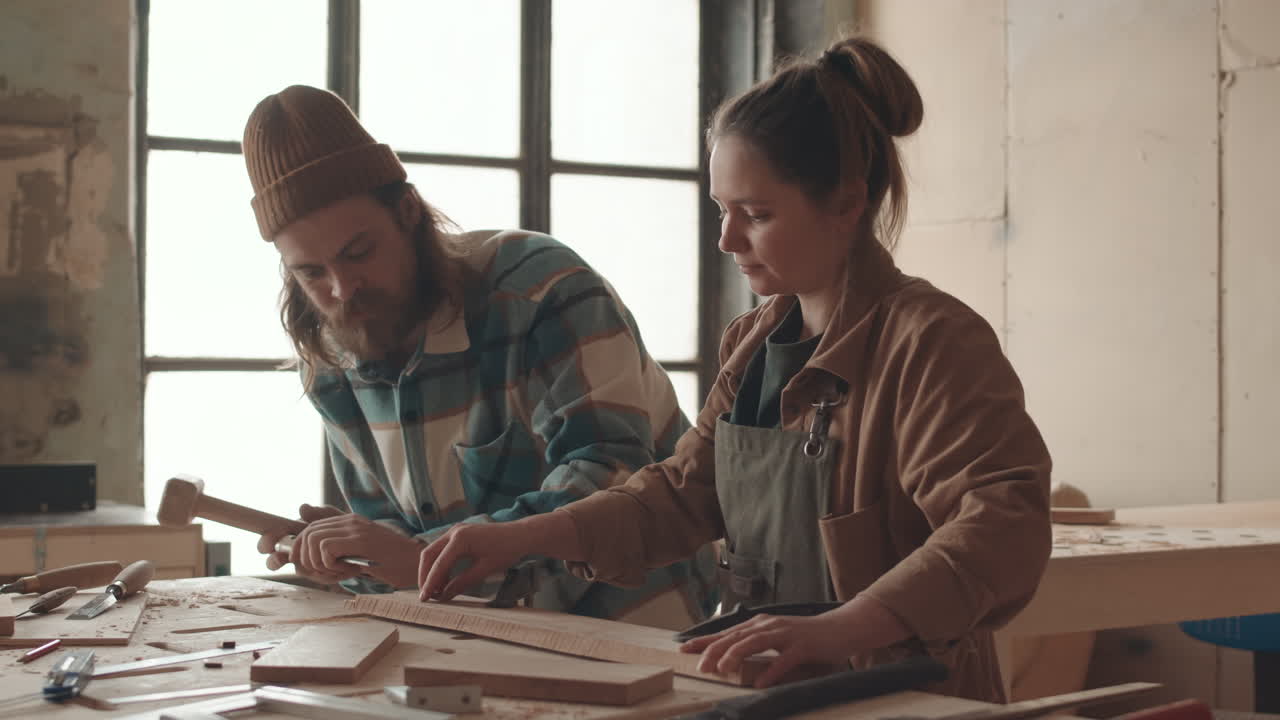 Young Woman Watching Professional Joiner Working in Carpentry Workshop