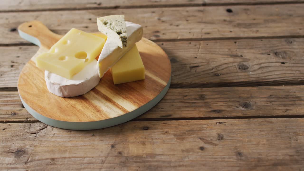 나무  ⁇ 기 보드와 농촌 테이블에 있는 다양한 단단하고 부드러운 치즈의 비디오, 복사 공간과 함께