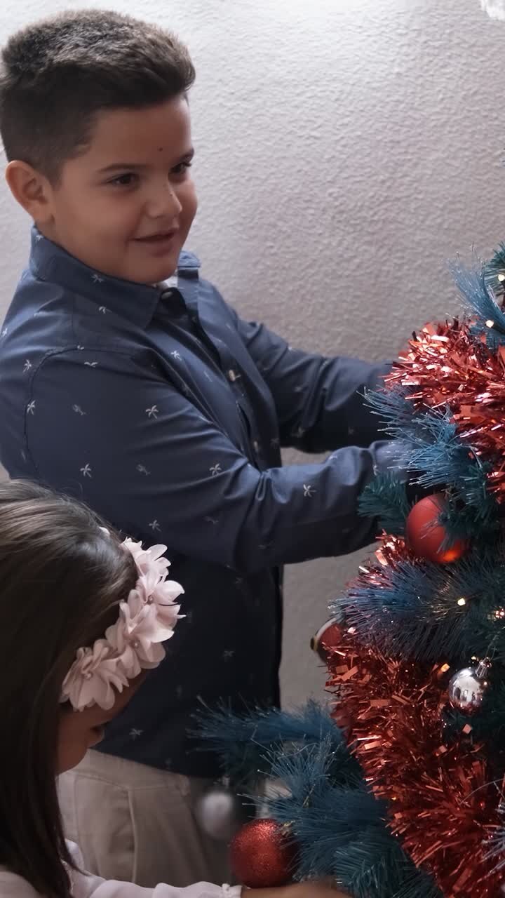Two happy kids decorating the christmas tree at home