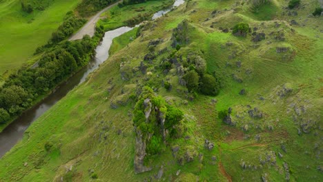 Geological-rock-features-sticking-out-from-grass-hill-in-New-Zealand,-aerial