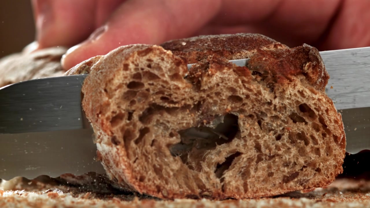 Primo piano al rallentatore del taglio di pane rustico con un coltello