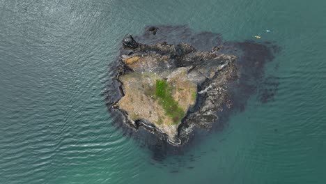 Eine-Drohnenaufnahme-Von-Oben-Nach-Unten-Von-Einer-Kleinen-Insel-Mit-Kajakfahrern,-Die-Sie-Umgeben