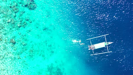 tourists snorkeling in the aquamarine seawaters near the boat over the coral reef