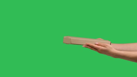 female hands giving cardboard box with pizza on background of green screen chroma key. close up of box with snack for dinner. fast courier delivery of food. advertising of pizzeria. slow motion