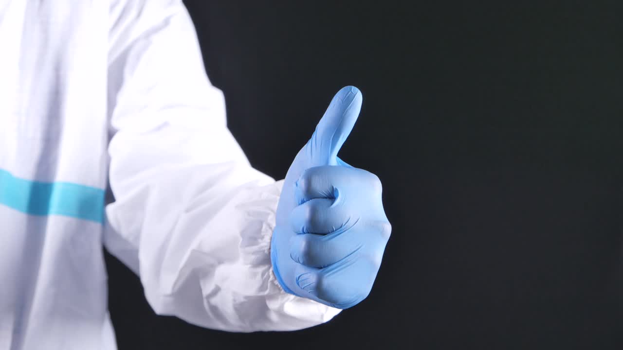 보호 장비를 입은 의사가 엄지손가락을 높이 들고