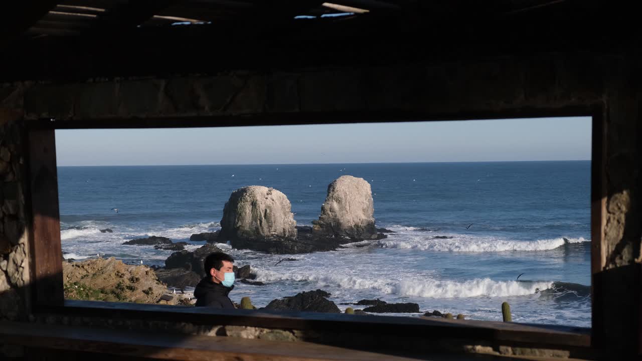 팬데 여행에서 얼굴 마스크를 착용한 남자가 칠레의 타 데 로보스 서핑 포인트 (punta de lobos surf point) 에서 새로운 정상적인 칠레에서 건강한 코로나 바이러스 무료 칠레 투스 (cactus pichilemu) 근처에서 여행하는 새로운 방법