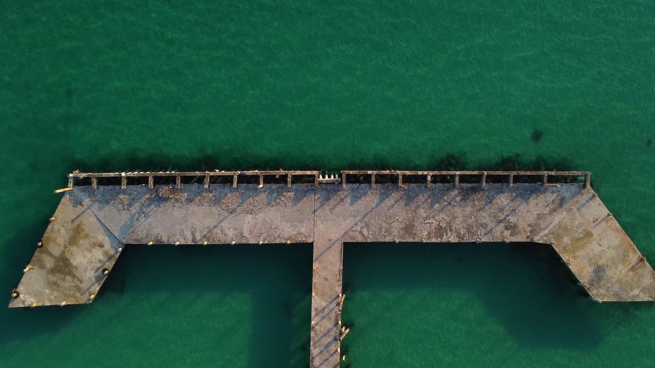 Wood deck pier over ocean water, observation point aerial top down view