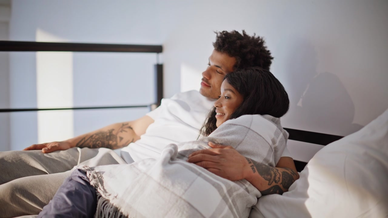 Teen couple cuddling bed enjoying domestic atmosphere closeup. Man woman hugging