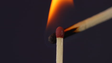 mano encendiendo un partido uno contra el otro súper primer plano macro capturado en fondo negro en cámara lenta a 60 fps