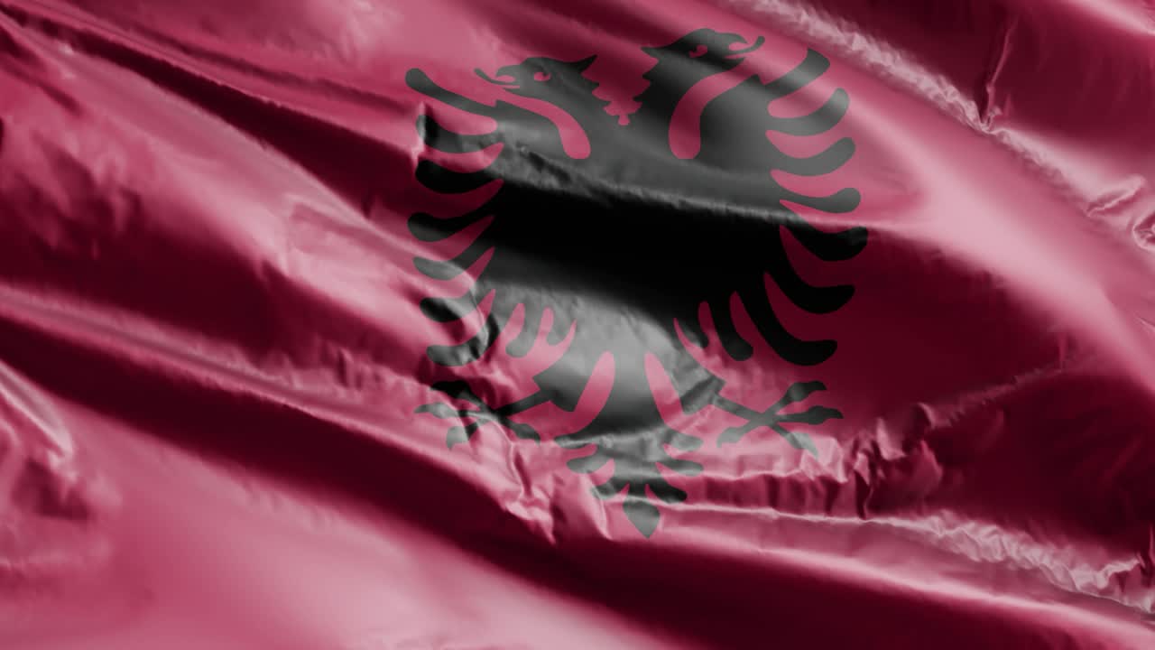 bandera de albania agitando lentamente en el bucle del viento. bandera albanesa balanceándose suavemente en la brisa. fondo de relleno completo. bucle de 20 segundos.