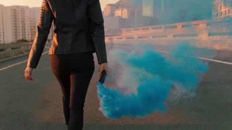 confident woman holding smoke grenade walking in city street at sunrise rebellious female activist protesting