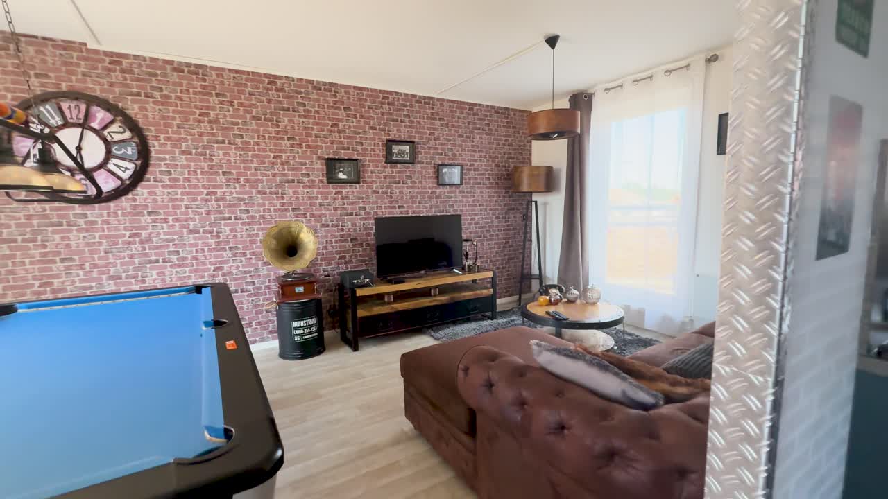 Camera glides through a vintage-inspired lounge featuring a brick wall, gramophone, pool table, and cozy seating, illuminated by natural daylight