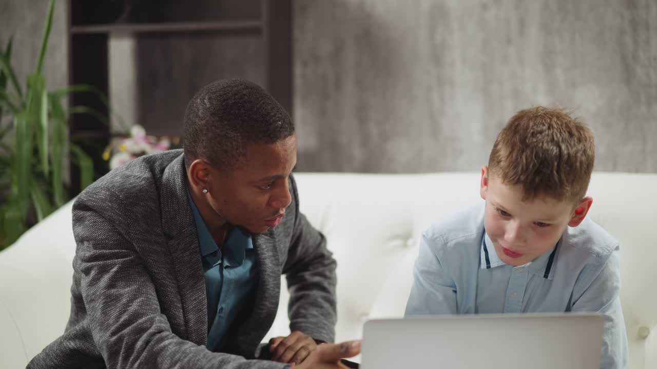 영어 를 모국어로 사용하는 교사 와 소년 학생 이 비디오 를 보십시오
