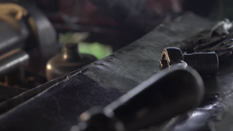 LOCKED-OFF-CLOSE-UP-view-of-nut-and-bolt-on-car-bonnet-with-welding-going-on-in-the-background