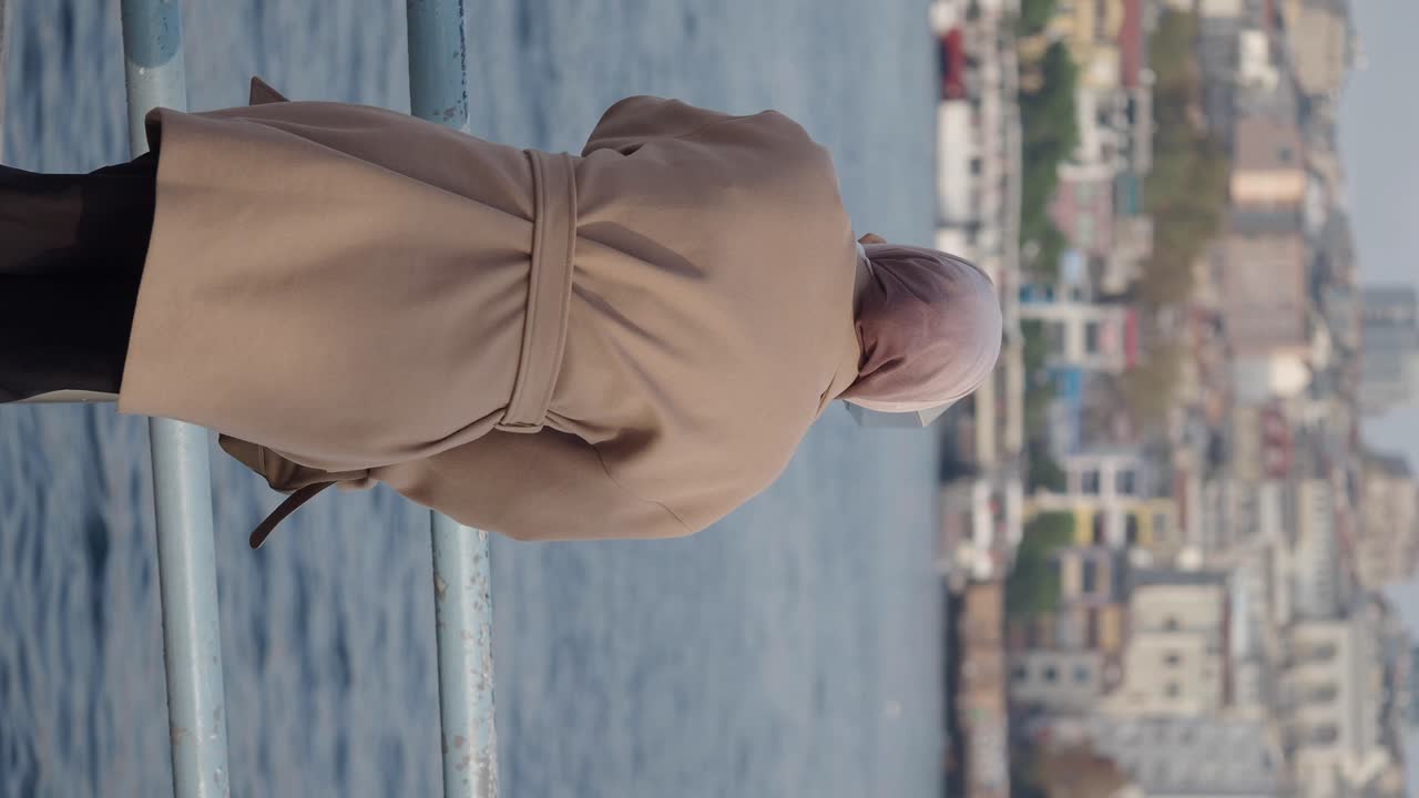 Woman in hijab looking at the cityscape and water