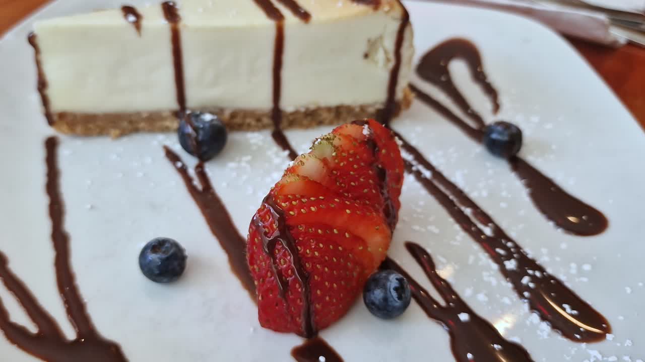 American Cheesecake With Chocolate Toppings, Strawberry and Blueberries on Plate, Close Up