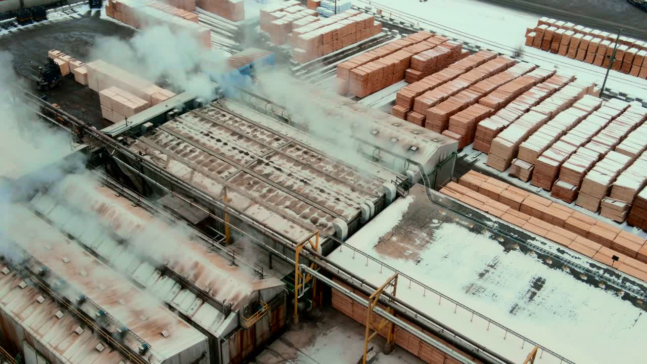 캐나다의 제재소 생산 현장에 있는 산업 건식 가마와 합판 더미의 오버헤드 샷