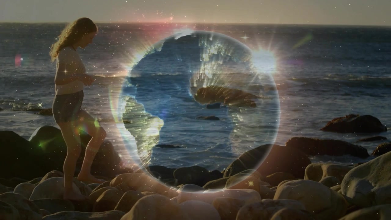 Un tramonto che scende all'orizzonte illumina un globo terrestre rotante su una costa rocciosa, mentre una donna osserva una demo tecnologica.