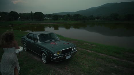 woman near a vintage car by a lake
