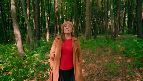 caucasian women with an overcoat and hat walking in the forest trail and enjoying the atmosphere