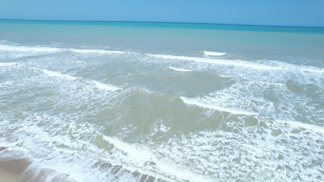 Aerial flight over the Caribbean Sea, the camera tilted straight down and moving forward over the waves.
